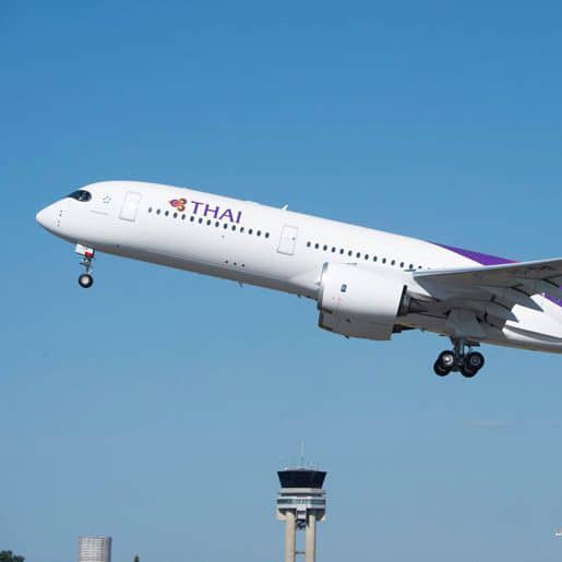 A Thai Airways plane is taking off from an airport.